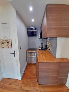 a small kitchen with wooden counter tops and a door at Très beau 2P avec vaste séjour ensoleillé - A 50 m du métro du marché et de la mairie in Clichy