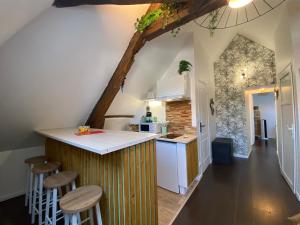 a kitchen with a wooden counter and stools at Sous les tropiques d’Ablis in Ablis