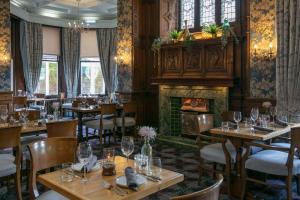 restauracja ze stołami i krzesłami oraz kominkiem w obiekcie Moor Hall Hotel, BW Premier Collection w mieście Sutton Coldfield