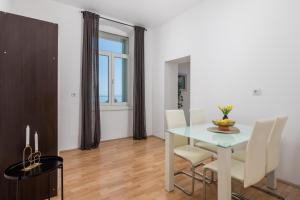 a white dining room with a table and chairs at Step to the Sea apartment in Rijeka