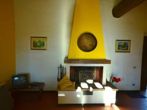 uma sala de estar com lareira e parede amarela em Serene farmhouse in Dicomano with swimming pool em Dicomano