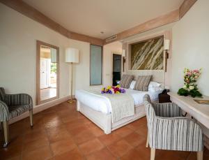a bedroom with a white bed and two chairs at Hotel Oasi Di Kufra in Sabaudia