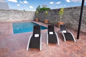 two chairs and a swimming pool in a backyard at La Quinta by Wyndham San Luis Potosi in San Luis Potosí