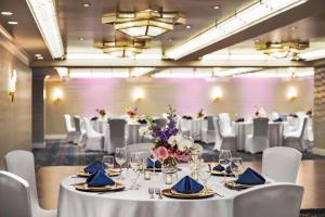 una sala de banquetes con mesas blancas y sillas blancas en Inn at Great Neck en Great Neck