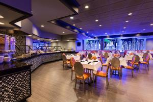 un restaurante con mesas y sillas blancas y un bar en Wyndham Garden Dallas North, en Dallas