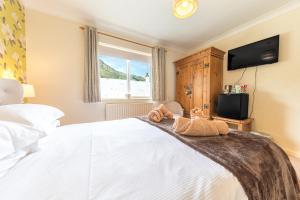 Meadowdore Stay B&B في كونيستون: غرفة نوم مع سرير مع اثنين من الحيوانات المحشوة عليه