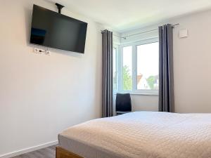 Schlafzimmer mit einem Bett und einem Flachbild-TV an der Wand in der Unterkunft Weiße Villen Wohnung 20 in Boltenhagen