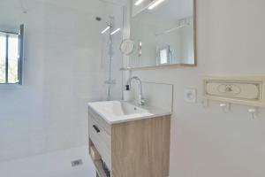 a white bathroom with a sink and a mirror at Maison Grand Large - A 800 m de la plage in Saint-Cast-le-Guildo