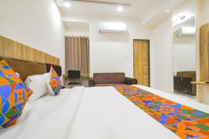 a bedroom with a large white bed with colorful pillows at FabHotel Suraj Kunj in Indore