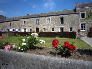 un antiguo edificio de piedra con flores en un jardín en Cosy Cottage in Barvaux Condroz with Garden, en Barvaux-Condroz