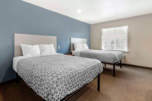 WoodSpring Suites Raleigh Garner في Edmondson: غرفة فندقية بسريرين ونافذة
