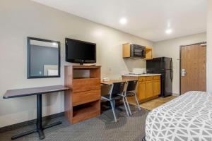a hotel room with a bed and a desk with a television at WoodSpring Suites Raleigh Garner in Edmondson +11 photos