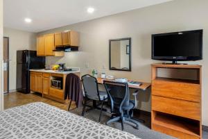 WoodSpring Suites Raleigh Garner في Edmondson: غرفة مع مطبخ مع مكتب وتلفزيون