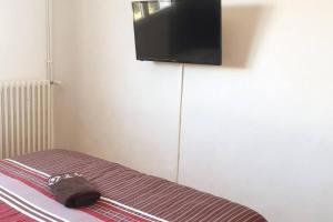 una bolsa sentada en una cama con un televisor en la pared en Maison familiale - ménage, serviettes, draps inclus, en Gaillac