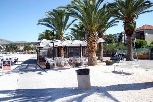 una playa con palmeras y un restaurante con mesas y sillas en Apartments Gavric, en Trogir