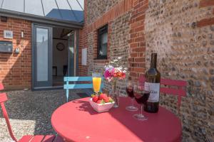 einen roten Tisch mit einer Flasche Wein und einer Schale Obst in der Unterkunft Kipper Cottage, Southwold in Southwold + 19 Fotos