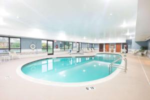 a large pool in a building with chairs and tables at Wingate by Wyndham Waynesboro in Waynesboro