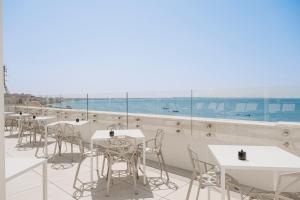 Biancodonda Lifestyle Hotel & SPA في غالّيبولي: صف من الطاولات والكراسي على سطح مطعم