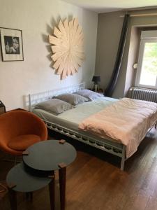 - une chambre avec un lit, une chaise et un lustre dans l'établissement Chez Hervé le Châtelet, à La Chaux Neuve