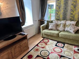 a living room with a couch and a flat screen tv at Bay View Cottage in St Austell