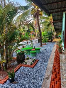 un jardin avec des palmiers, des plantes et du gravier dans l'établissement ครูไสวโฮมสเตย์, 