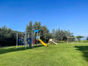 a playground with a slide and swings on a grass field at Casa Elegancia Pleta de Saga in Ger