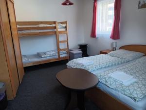 a bedroom with two bunk beds and a table at Penzion Pod Hamižnou in Hartmanice