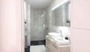 La salle de bains blanche est pourvue d'un lavabo et d'une douche. dans l'établissement Sommeiller à 2 min du Lac, à Annecy