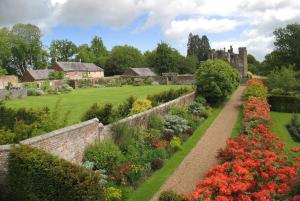 a garden with flowers and a castle in the background at Castle Cottage, Wadhurst in Wadhurst