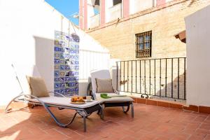 un patio con 2 sillas y una mesa en el balcón en Casa de los Venerables en Sevilla