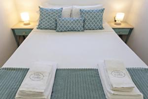 een slaapkamer met een wit bed en 2 nachtkastjes bij Villa Lydia in Praia de Faro +10 foto's
