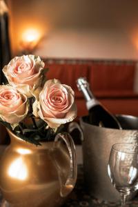 a vase filled with pink roses and a bottle of champagne at Hotel Liberty in Spresiano
