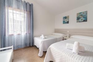 Dieses weiße Zimmer verfügt über 2 Betten und ein Fenster. in der Unterkunft Moderno apartamento en Playa de los Cancajos in Los Cancajos