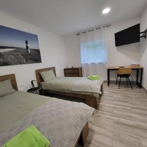 a room with two beds and a desk and a television at HOSTEL Postaja in Ruše