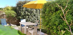a table and chairs with a yellow umbrella at Gite de Kervao, Hortensias avec jardin privatif, Plage 700 m in Ploudalmézeau