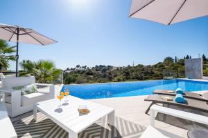 eine Terrasse mit einem weißen Tisch und Stühlen sowie einem Pool in der Unterkunft Villa Boa Vida by Algarve Vacation in Armação de Pêra