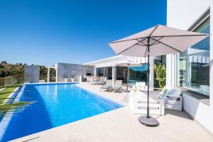 ein Sonnenschirm und Stühle neben einem Pool in der Unterkunft Villa Boa Vida by Algarve Vacation in Armação de Pêra