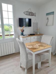 a dining room table with two chairs and a tv at Studio proche du centre ville et de la plage in Villers-sur-Mer