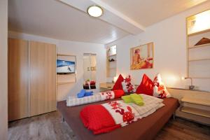 sypialnia z łóżkiem z białymi i czerwonymi poduszkami w obiekcie Apartment Rossbichl w Saalbach Hinterglemm