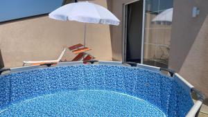 a blue swimming pool with an umbrella and a chair at Ada’s house in Durrës