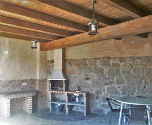 una chimenea de piedra en un patio con mesa y sillas en Casa Armonia, en Ávila