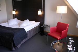 a hotel room with a bed and a red chair at Hotel Sørup Herregaard in Ringsted
