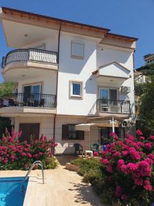a large building with a swimming pool and flowers at Manolyam suit havuzlu 2+1 in Kaş