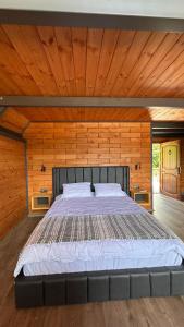 Cama grande en habitación con paredes de madera en Garvela Bungalow, en Artvin