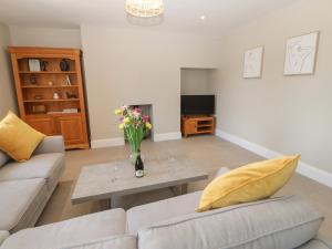 a living room with a couch and a table with flowers at The Old House in Northallerton