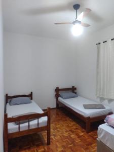 een kamer met 2 bedden en een plafondventilator bij voltamos a funcionar casa da mãe Aparecida in Aparecida