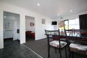 a living room with a table and chairs and a bedroom at Brown Trout Motel in Pahiatua