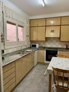 a kitchen with wooden cabinets and a sink and a table at Apartamento Cambrils Centro in Cambrils