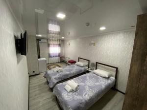 pokój z dwoma łóżkami i telewizorem w obiekcie HOTEL UZBEGIM w Urgenczu