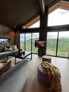 a living room with couches and a tv and windows at Sogndal Chalet in Sogndal